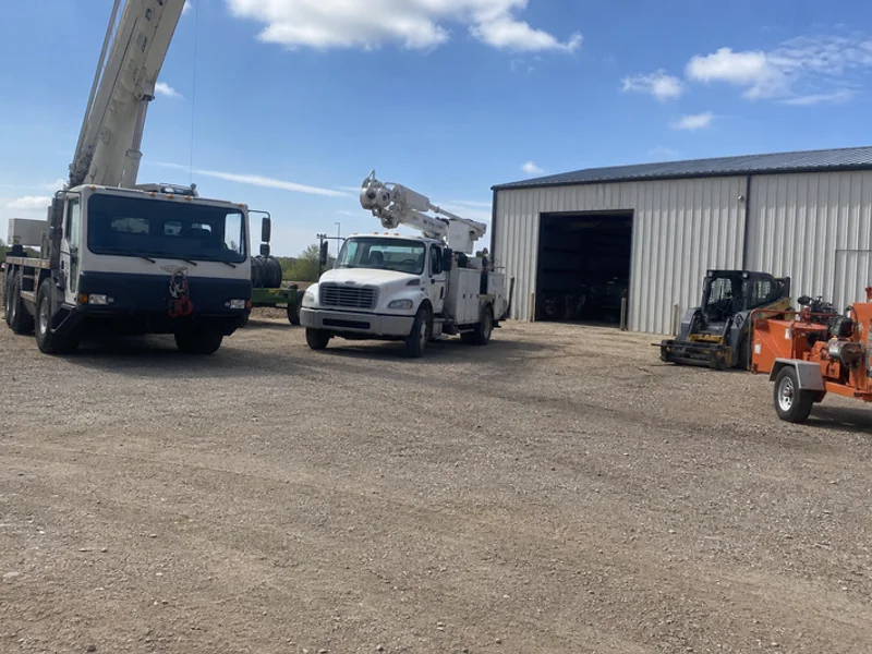 Equipment yard with crane, bucket truck, and chipper